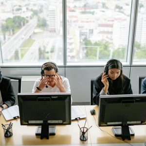 Group of diverse call center employees working at computers in a modern office setting.