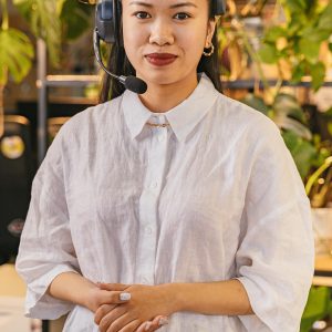 Smiling businesswoman with headset providing customer support in a modern office setting.